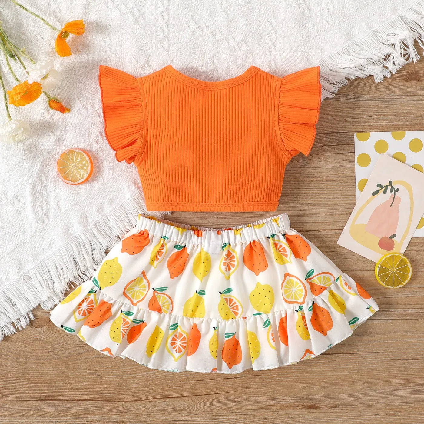 2pcs Baby Girl Solid Cotton Ribbed Ruffle-sleeve Twist Knot Crop Top and Allover Fruit Print Skirt Set